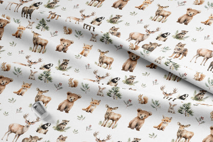 Cute woodland animals fabric with deer, bears, foxes, raccoons, and squirrels. The watercolor-style illustrations are in shades of brown, tan, and green, with small evergreen trees and floral accents. Made in the USA by American Fabric Prints. Shop now.